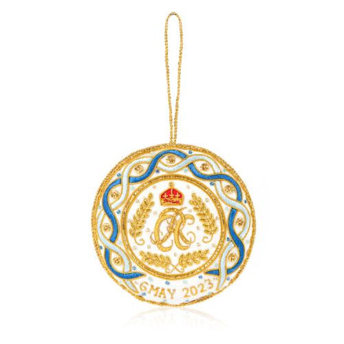White decoration with blue and gold stitching. Joint cypher of their majesties at the centre and the date of the coronation at the bottom.