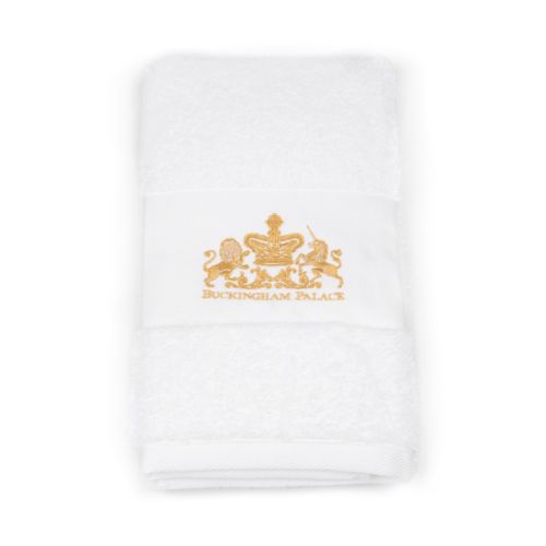 White hand towel with gold embroidered coat of arms at the centre. Wrapped with white and gold label.