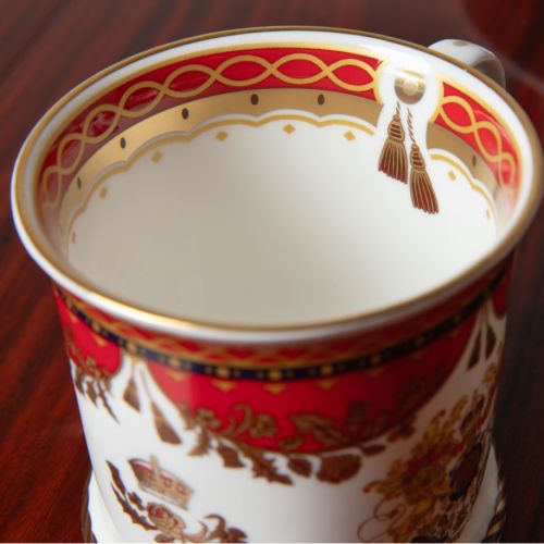 The Livery Takard, featuring the royal coat of arms 
 with a deep, rich scarlett design and navy border with contrasting fine gold details, inspired by the intricate decorative braiding of hand-sewn livery and regimental devices of ceremonial uniforms. 